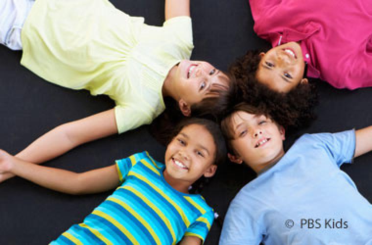 four children lying down with thier heads together in a circle