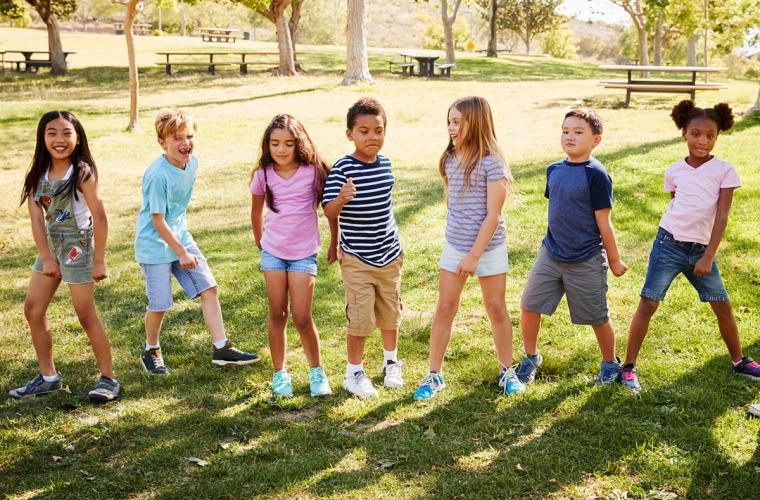 Multicultural kids dancing outside on the grass