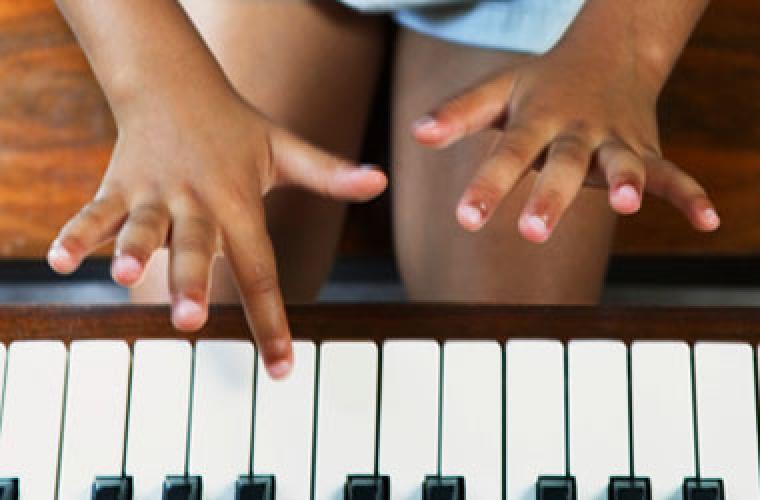 Close-up of young child's hands playing the piano