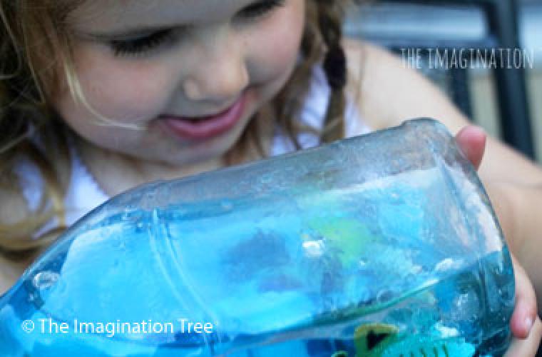 little girl holding a bottle fillied with water and fish