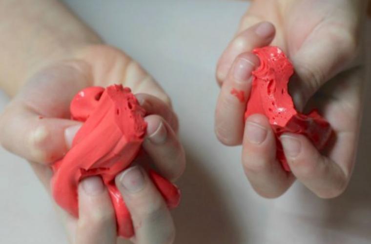 Close-up of child's hands with red silly putty