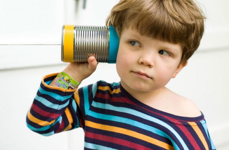 Child listening to a tin can telephone on a string