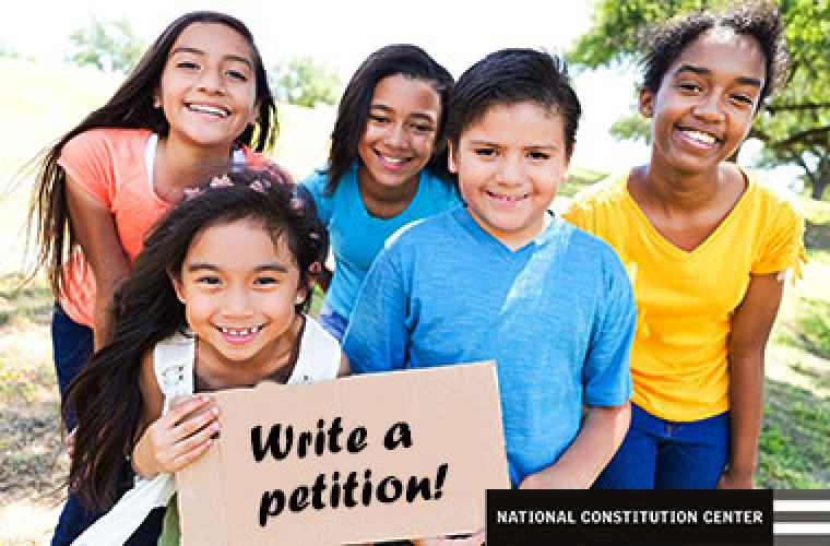 photo of five children holding a cardboard sign that says write a petition