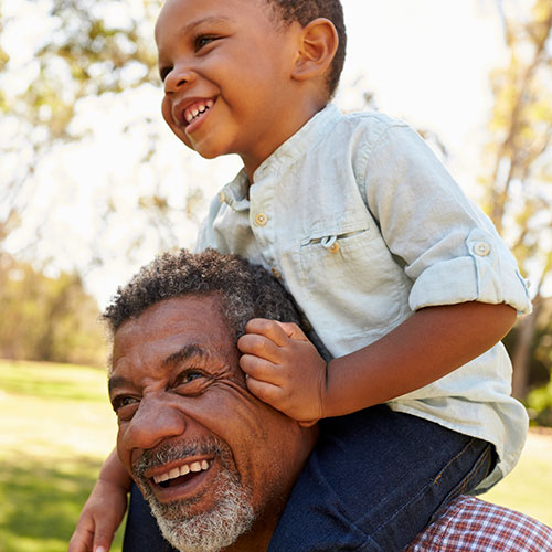 Boy riding older man's shoulders.